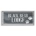 Stupell Industries Black Bear Lodge Sign Rustic Animal Footprints Wall Plaque Art By Kim Allen Wood in Brown | 1.5 D in | Wayfair af-899_gff_10x24