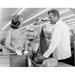 Mid adult woman and a male sales clerk at the checkout counter in a super market Poster Print (24 x 36)