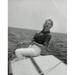 Side profile of young woman sitting on edge of boat and smiling Poster Print (24 x 36)