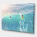 DESIGN ART Designart Surfers On A Bright Sunny Ocean Wave Traditional Canvas Wall Art Print 44 in. wide x 34 in. high