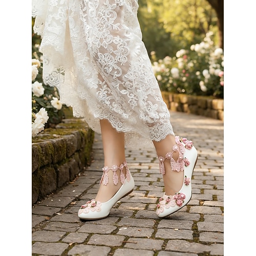 Elfenbeinfarbene, geblümte Damen-Ballerinas mit Knöchelriemen, romantische Brautschuhe für eine Gartenhochzeit im Freien Image